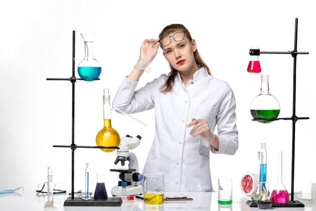 微笑前视图身着医疗服的女化学家在工作过程中用白色背景上的溶液化学大流行的柯维病毒医生正面套装