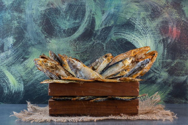 烧烤一盒干鱼放在大理石表面的粗麻布餐巾上薯条盒子海鲜