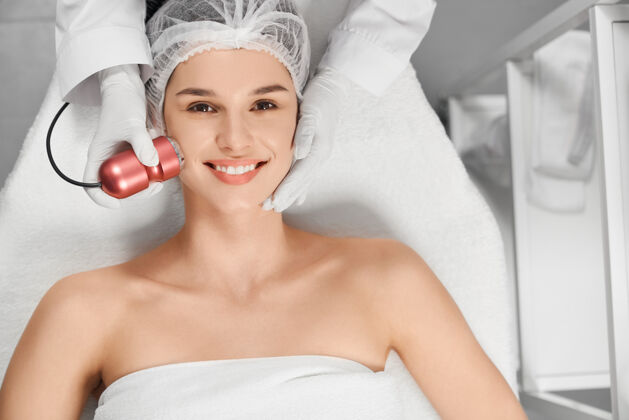皮肤满意美女在美容师的程序上面膜护理快乐