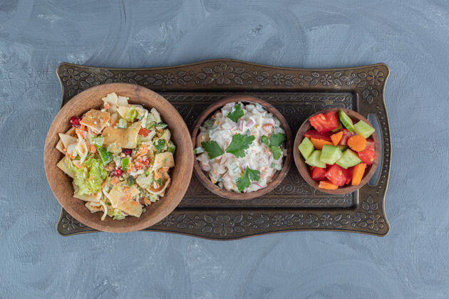 碗在大理石桌上的木制碗里放一份混合蔬菜 奥利弗沙拉和牧羊人沙拉美味美味晚餐