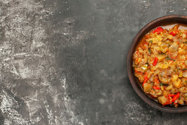 肉黑暗表面上碗里烤茄子沙拉的俯视图饭荷兰烤箱晚餐