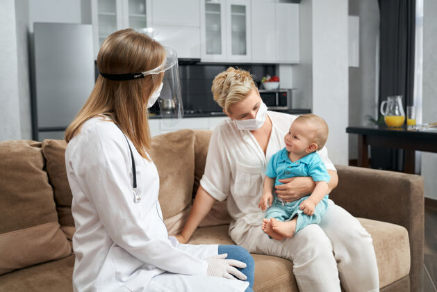 手套戴着医用口罩的儿科医生在家探望宝宝医生成熟儿子