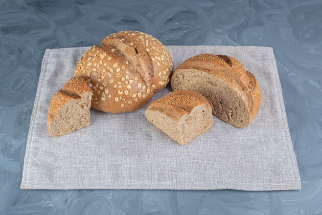 芝麻整条面包和切片面包捆在大理石桌上的毛巾上好吃的好吃的烤面包