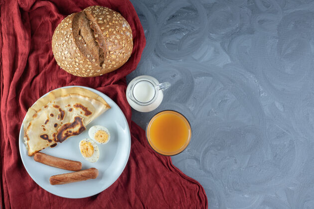 香肠薄饼 香肠和煮蛋片 旁边放着牛奶 果汁和面包 放在大理石桌上薄煎饼可口面包