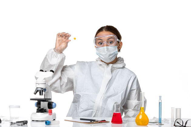 病毒正面图：穿着防护服 戴着口罩的女医生拿着白色背景上的样本病毒药物covid-大流行制服药品口罩