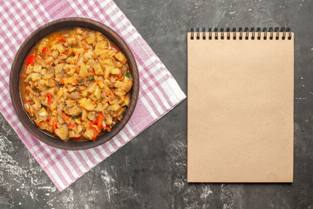 食物碗里烤茄子沙拉的俯视图一个笔记本在黑暗的表面上深色健康农产品
