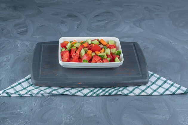 黄瓜在大理石桌上放着一盘羊肉沙拉和胡萝卜片的海军蓝托盘美味蔬菜西红柿