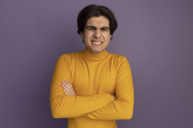 感觉微笑的年轻帅哥穿着黄色高领毛衣双手交叉隔离在紫色的墙上人交叉高领毛衣