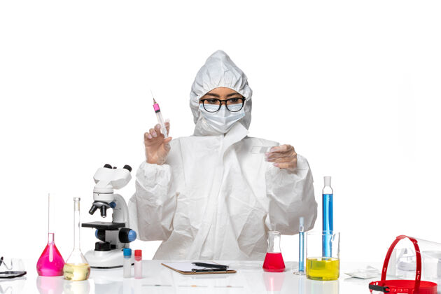 正面前视图穿着特殊防护服的女化学家在白色背景的化学病毒实验室里处理溶液和注射套装工作医生