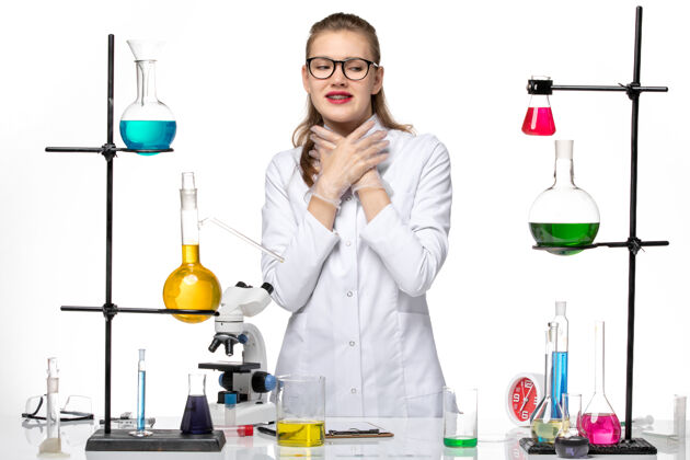 医疗前视图穿着医疗服的女化学家刚刚在白色办公桌上摆姿势化学病毒大流行性柯维德-诊所医生专业