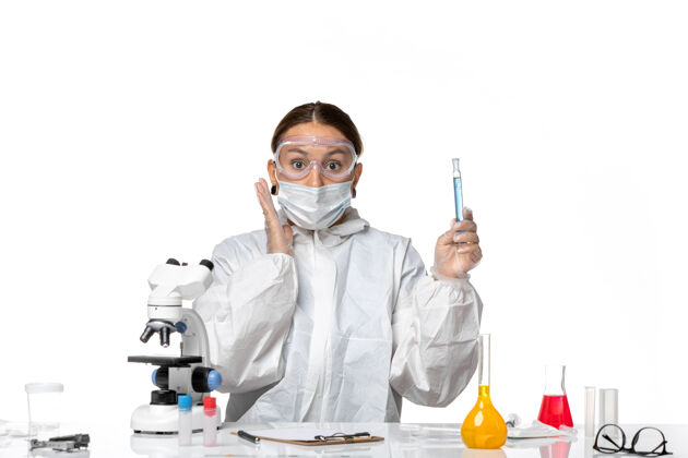 病毒前视图：女医生穿着防护服 戴着口罩 拿着装有淡白色背景病毒冠状病毒溶液的烧瓶医学外套保护