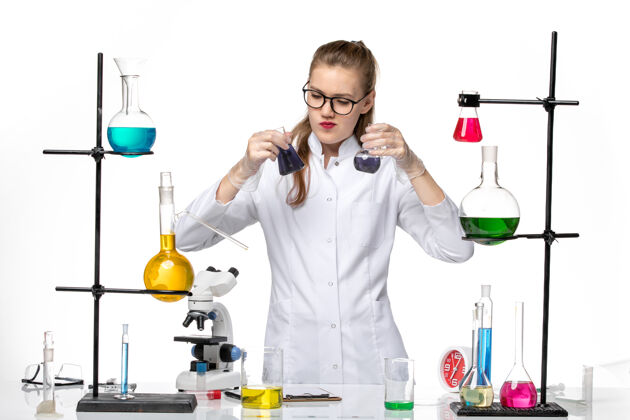 医学前视图穿着医疗服的女化学家在白色背景上用不同的溶液处理化学大流行的病毒女化学家前面工作