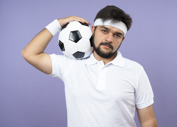 穿自信的年轻人戴着头带和腕带把球放在肩膀上运动头带自信