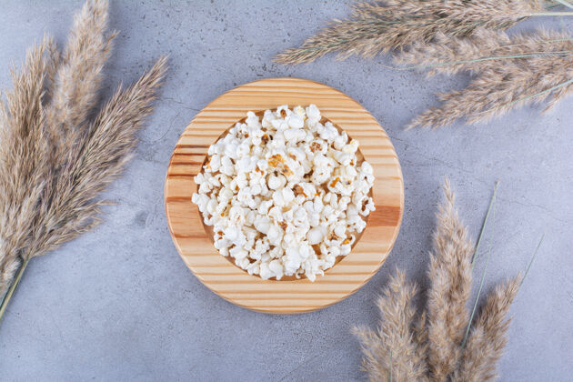 香料一盘爆米花被干草包围在大理石表面谷物黄油盐