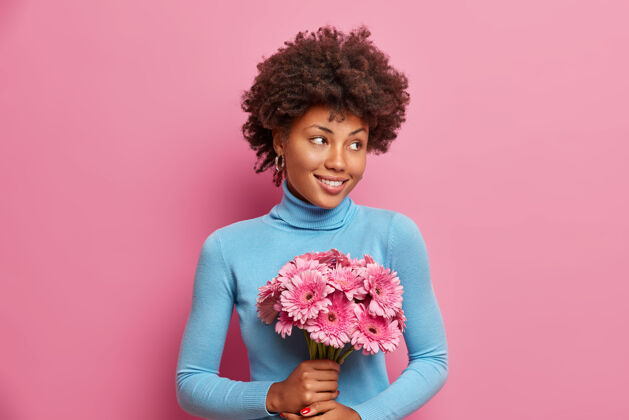 花束快乐浪漫的非裔美国妇女手持非洲菊花束领花礼物姿势粉色