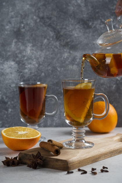 有机从透明的玻璃茶壶里把茶倒进玻璃杯子里黄色提神茶