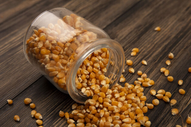 谷物有机和新鲜玉米粒的俯视图从一个玻璃罐里掉在一张木桌上内核新鲜食品