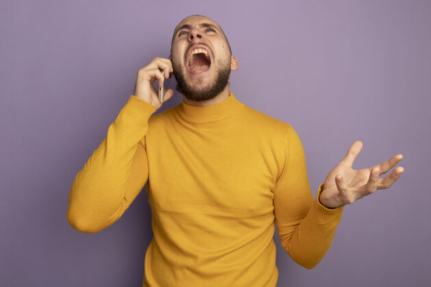 电话愤怒的抬头年轻帅哥在电话里说话 手被隔离在紫色的墙上愤怒帅哥说话