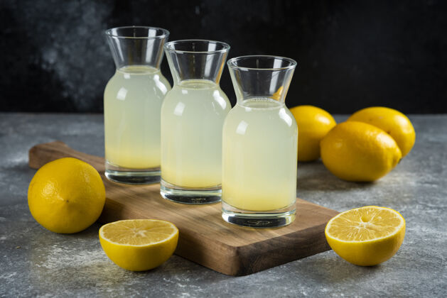 酸味三个装着美味柠檬水的玻璃罐放在木板上切片水果液体