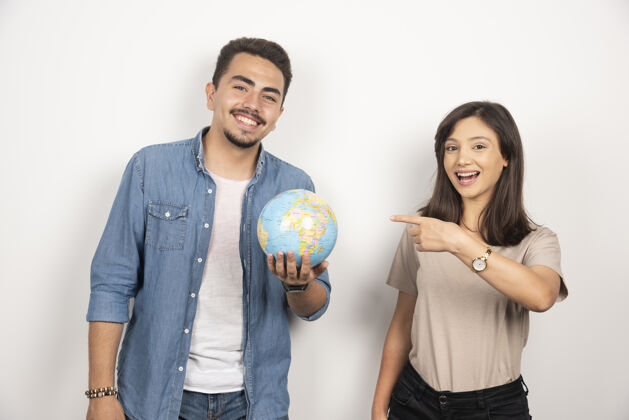 男人微笑的男人拿着一个地球仪在积极的女孩旁边女人地球仪男人