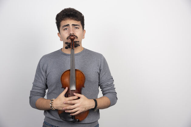 聪明一个音乐家拿着他的棕色木制小提琴 看起来很紧张失望独奏抑郁