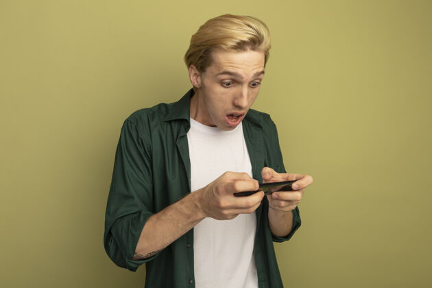 金发一个穿着绿色t恤打电话的金发小伙惊讶不已年轻男人手机
