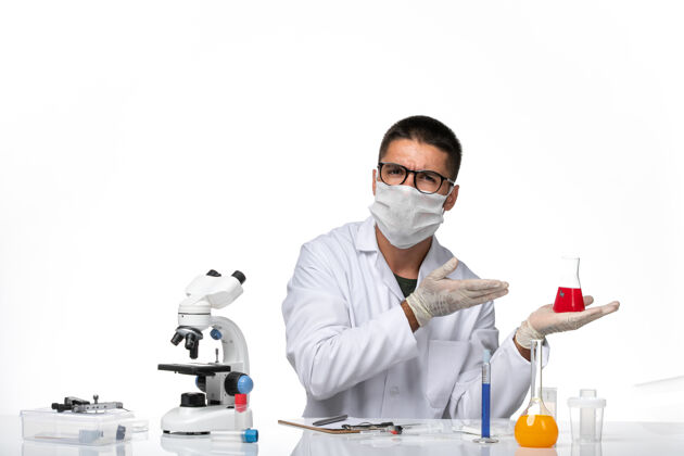 实验室正面图：男医生穿着白色医疗服 戴着口罩 坐在白色办公桌上医院专业健康