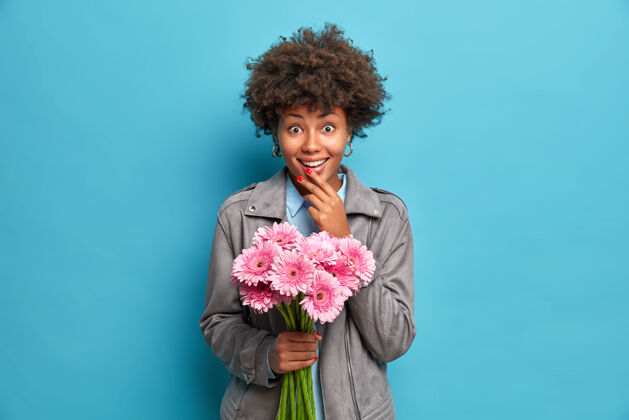 一个时尚年轻的非洲裔美国女人在约会期间收到一束粉色非洲菊花 这束花来自爱你的男朋友新鲜人微笑