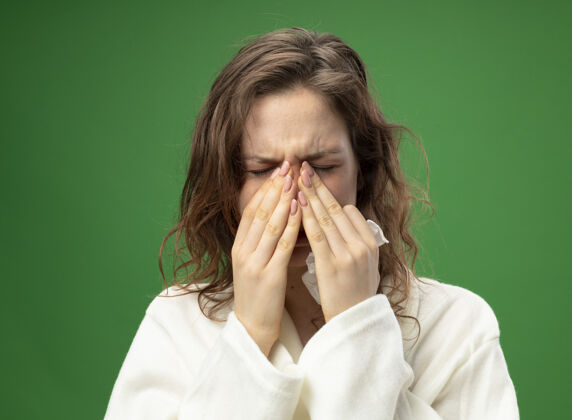 穿打喷嚏的年轻生病的女孩穿着白色的长袍 手放在鼻子上 隔离在绿色上抱鼻子手