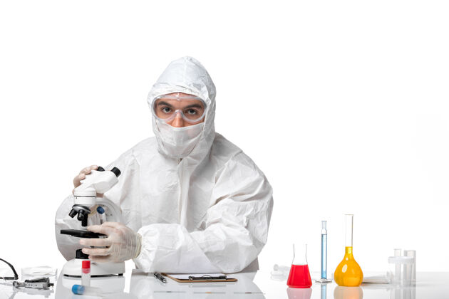面罩正面图：男医生穿着防护服 戴着面罩 在空白处用显微镜观察制服药人