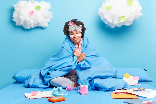 房子快乐的非洲裔美国妇女裹着柔软的羽绒被微笑着愉快地享受舒适的床上的家庭气氛的姿势室内蒙眼日记