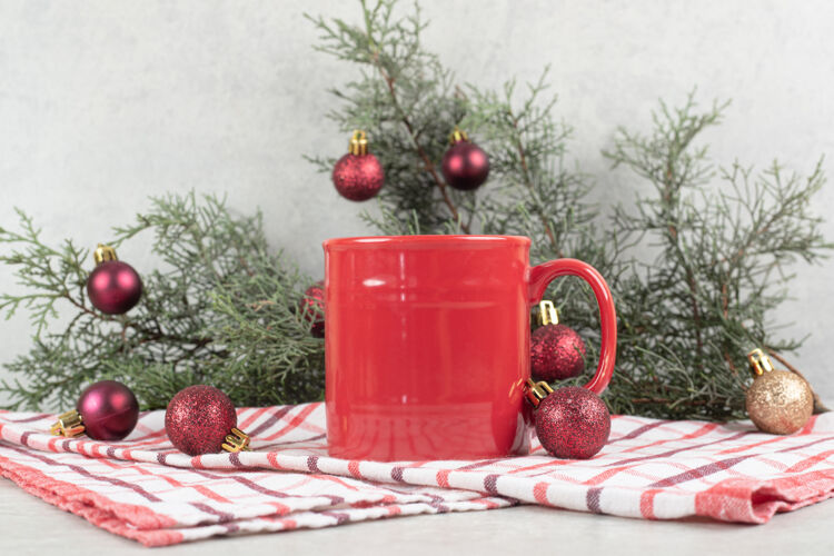 节日台布上的红色咖啡杯 有圣诞球和松枝圣诞节咖啡装饰