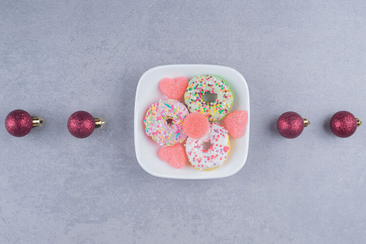 圣诞节一排圣诞饰品和一个甜点盘在大理石表面美味甜点糖