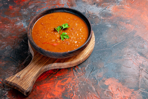 右在一个棕色的切菜板上的番茄汤在一个混合颜色的桌子右侧的侧视图蔬菜混合物餐厅