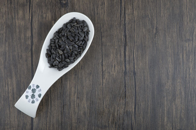 素食白勺健康的黑色葵花籽放在木桌上健康烤种子