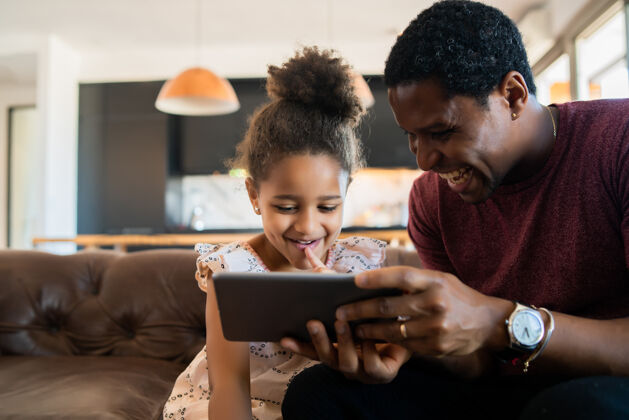 父亲一个女儿和父亲在家里玩数字平板电脑的照片一起玩耍平板电脑