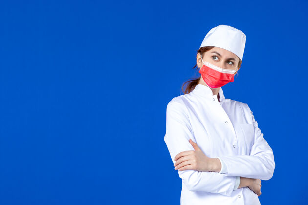 疾病正面图：穿着医疗服的年轻护士 蓝色的面具上戴着红色的面具面具大流行医学