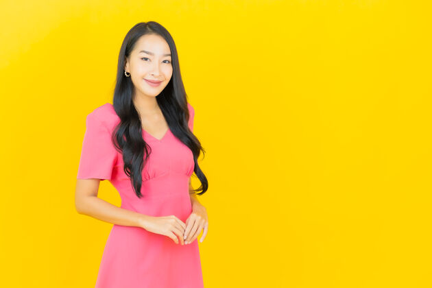 充满活力黄色墙壁上 美丽的亚洲年轻女子身着粉色连衣裙微笑的画像中国人模型女性