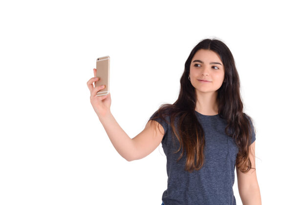 手机一个年轻漂亮的女人的自拍与她的手机在工作室隔离的肖像自我漂亮欢呼