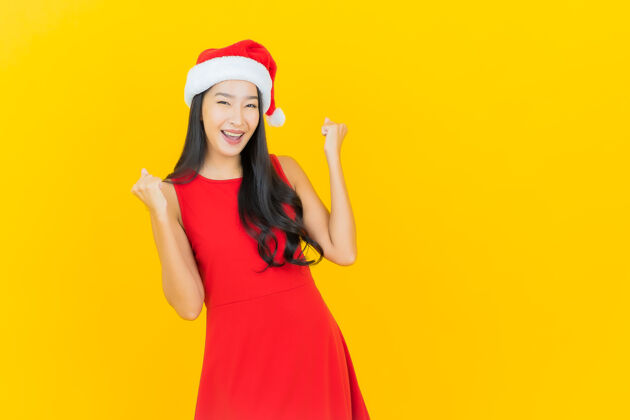 表情肖像美丽的亚洲年轻女子戴圣诞帽或发带在黄色的墙上圣诞老人中国年轻