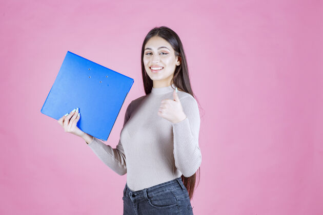 交易女孩拿着一个蓝色的项目文件夹 看起来很成功和快乐休闲清单积极