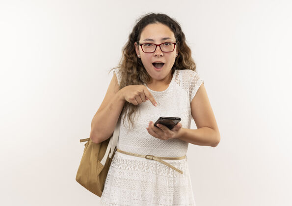 手机印象深刻的年轻漂亮的女学生戴着眼镜 背着书包拿着手机指着白色的隔离印象穿着指着