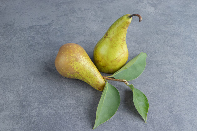 充满活力两个成熟的红黄色的梨果实被隔离在一个灰色的表面上新鲜成对健康