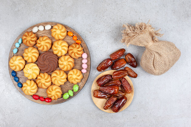 糕点一捆枣子和一个袋子 袋子里放着一块木板 木板上装饰着糖果和饼干 背景是大理石高质量的照片饼干袋子水果