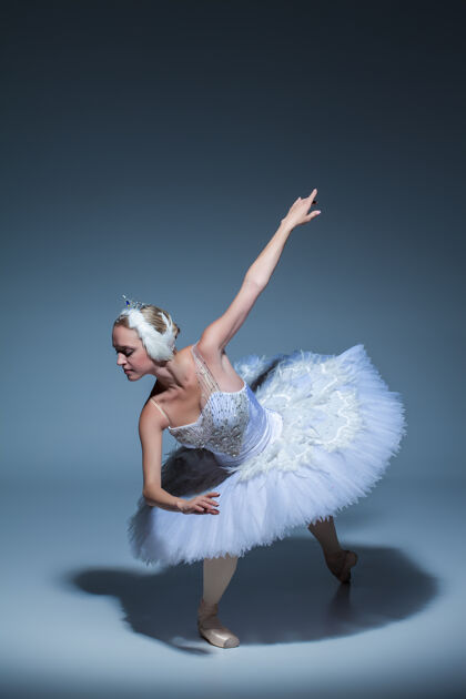 肖像芭蕾舞演员在蓝色背景下扮演白天鹅的肖像优雅姿势服装