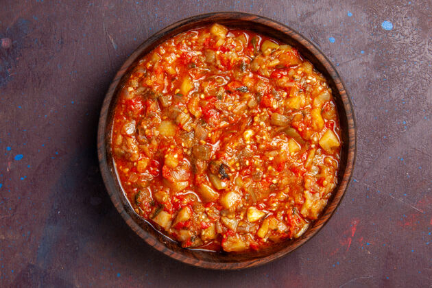 烹饪俯瞰美味的熟蔬菜酱汁餐 在深色背景上用蔬菜片做酱汁餐切片西红柿晚餐