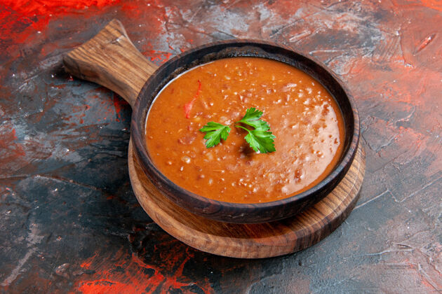 晚餐番茄汤放在一个棕色的砧板上 在一张五颜六色的桌子的右边番茄汤美食切