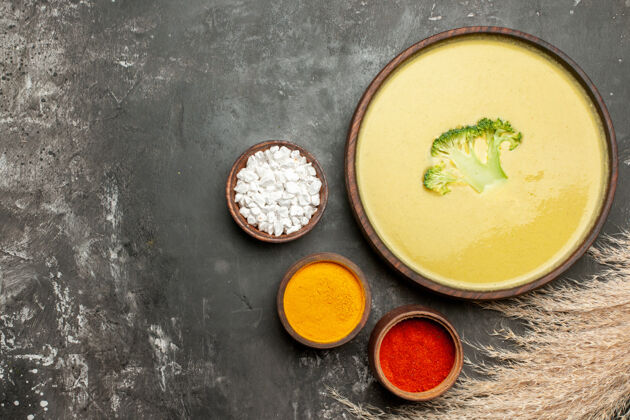 汤棕色碗里的奶油西兰花汤和灰色桌子上不同香料的水平视图碗镜头午餐