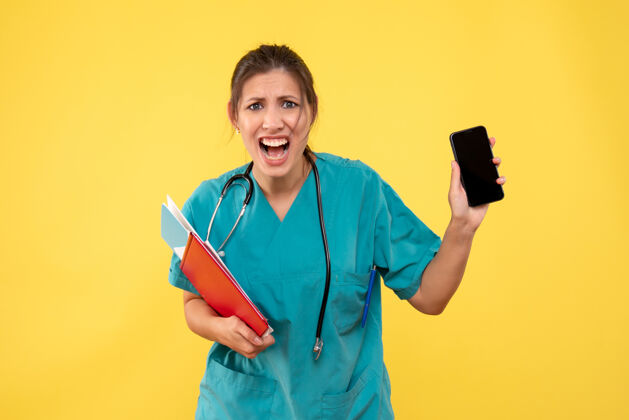 病毒前视图穿着医疗衬衫的女医生拿着黄色背景上的分析和电话持有衬衫情绪