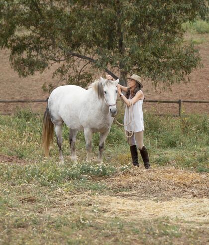 牧场女农夫抚摸她的马的侧视图女农民垂直老人